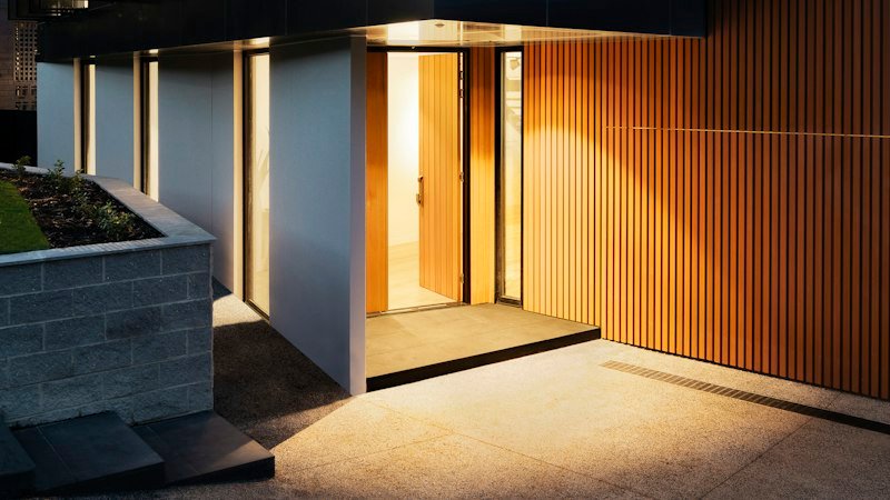 Cumberland House at dusk, the lit entry set between board-formed concrete and vertical cedar cladding