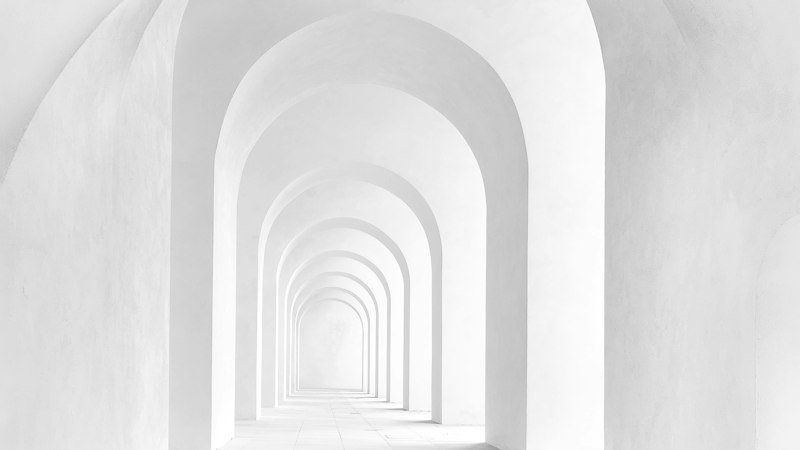 Pilgrim Chapel: a run of masonry arches receding down the nave, lit from a single source out of view